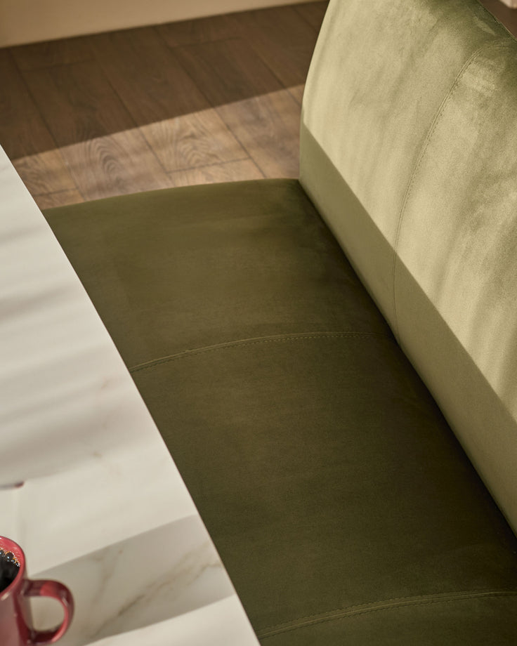 Olive green velvet bench with backrest, angled view showing seat cushion and back support on wooden flooring.