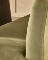 Olive green velvet bench with curved backrest and stainless steel leg, close-up detail view.