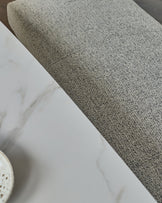Grey fabric 3-seater bench without backrest, close-up detail of textured upholstery and stainless steel base.