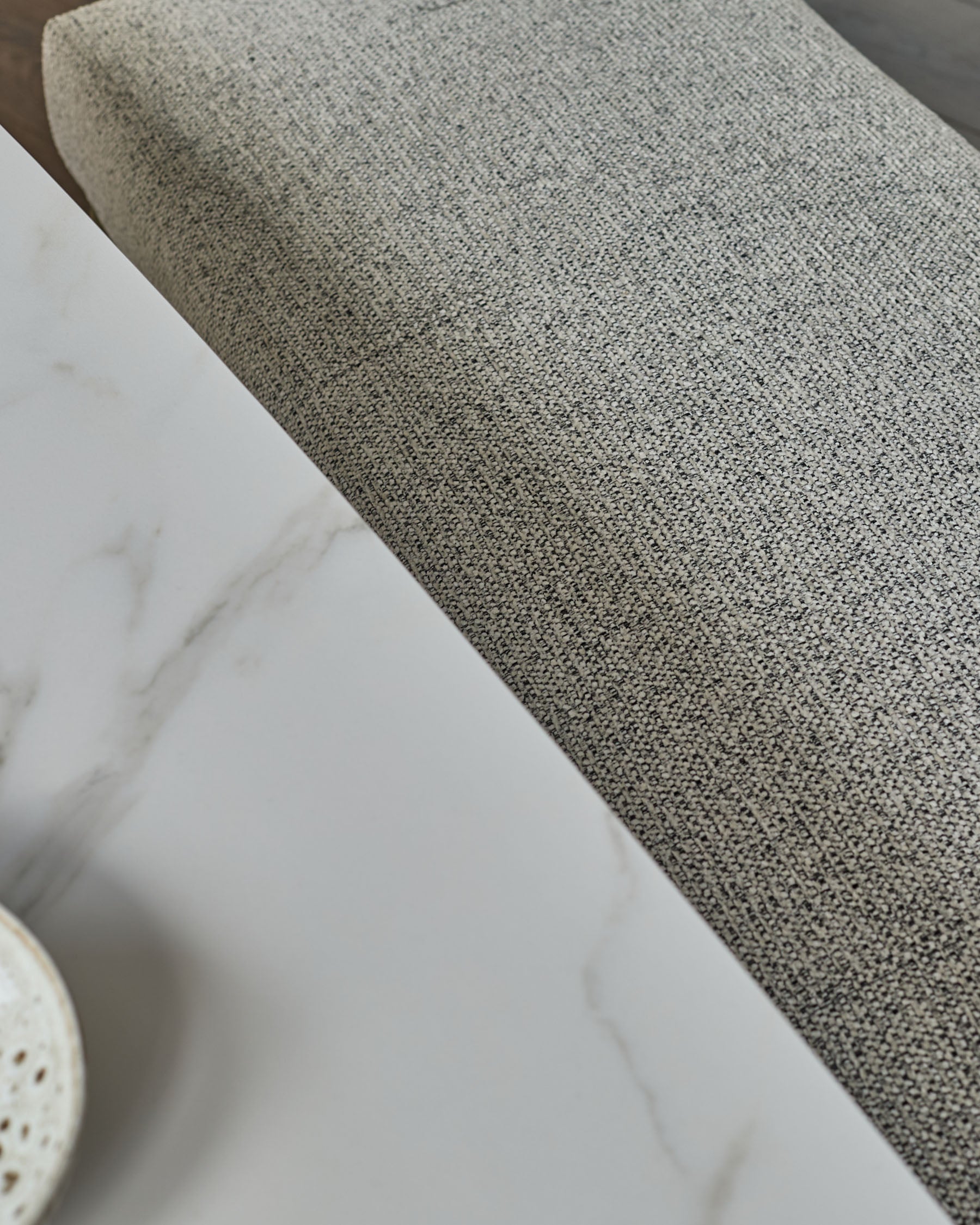 Grey fabric 3-seater bench without backrest, close-up detail of textured upholstery and stainless steel base.