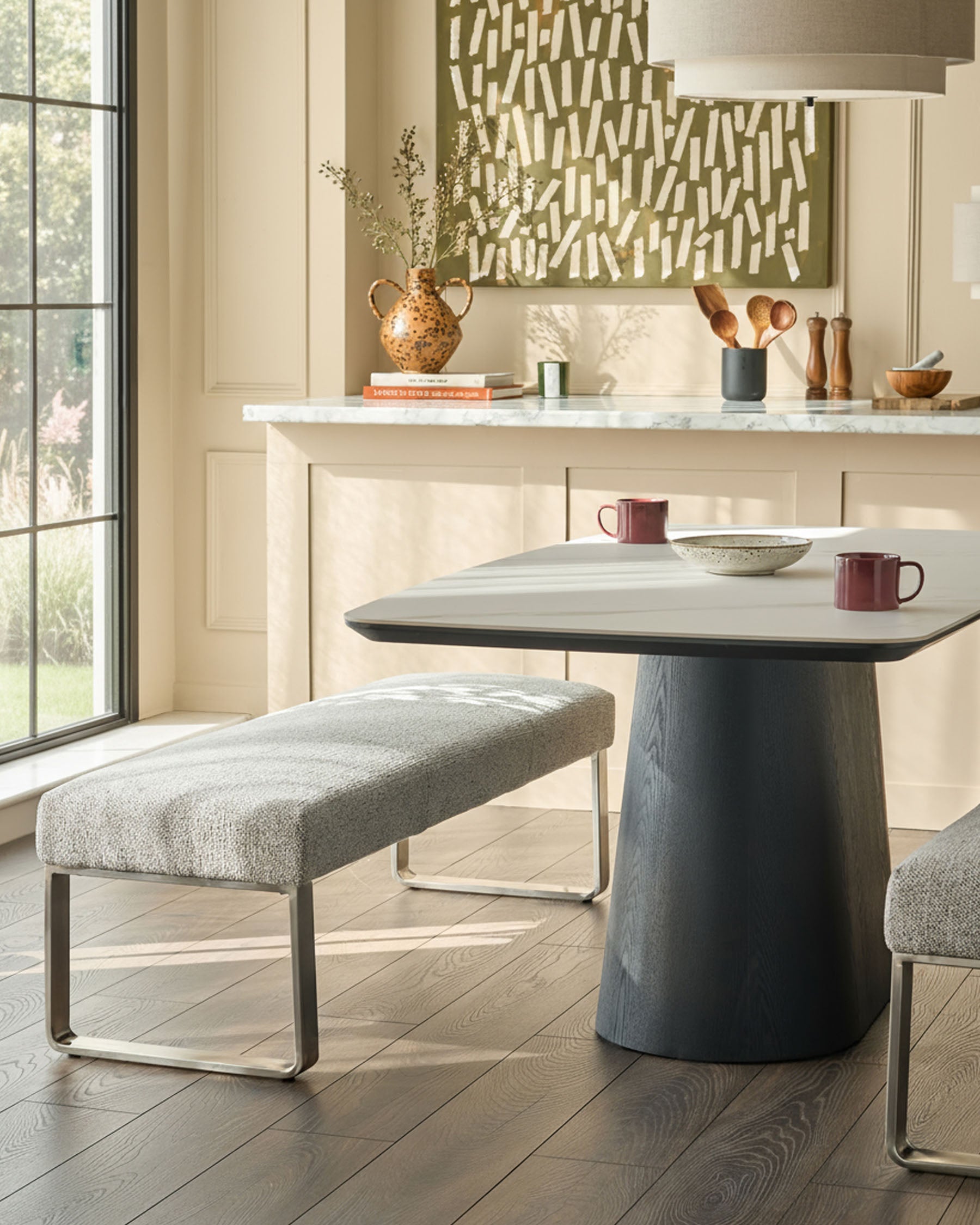 Loop 3-seater fabric bench without backrest in grey, stainless steel base, shown in modern kitchen setting.