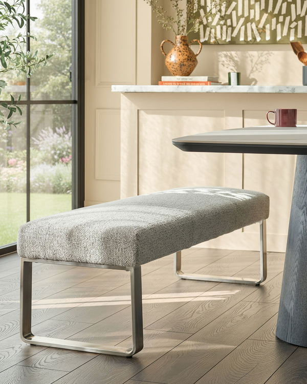 Loop 3-seater fabric bench without backrest in grey with stainless steel frame, shown in modern dining setting.