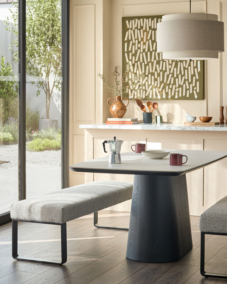 Loop 3-seater fabric bench without backrest in grey, featuring black metal frame legs, shown in a modern kitchen setting.