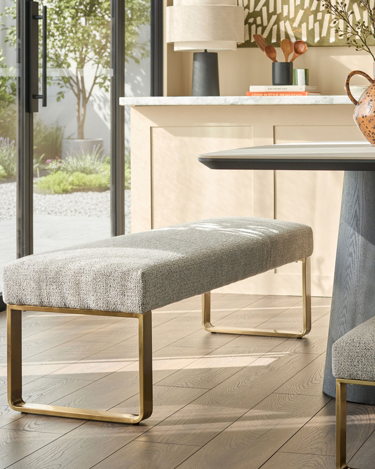 Loop 3-seater fabric bench without backrest in grey with brushed brass legs, shown in a modern living room setting.
