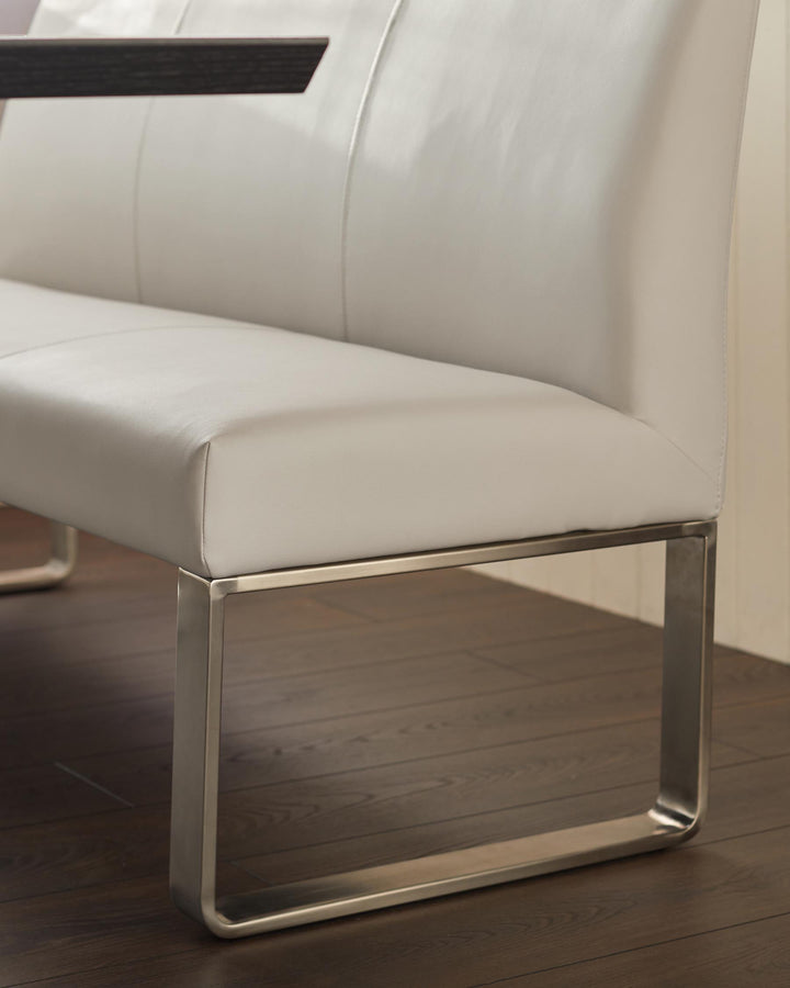 Close-up of a modern white leather bench with a stainless steel frame, highlighting its sleek design and quality materials.