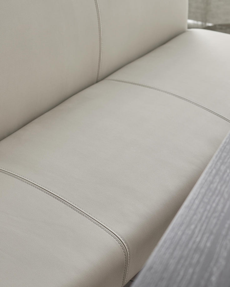 Close-up of a light grey leather sofa, showcasing its sleek design and comfortable cushioning.