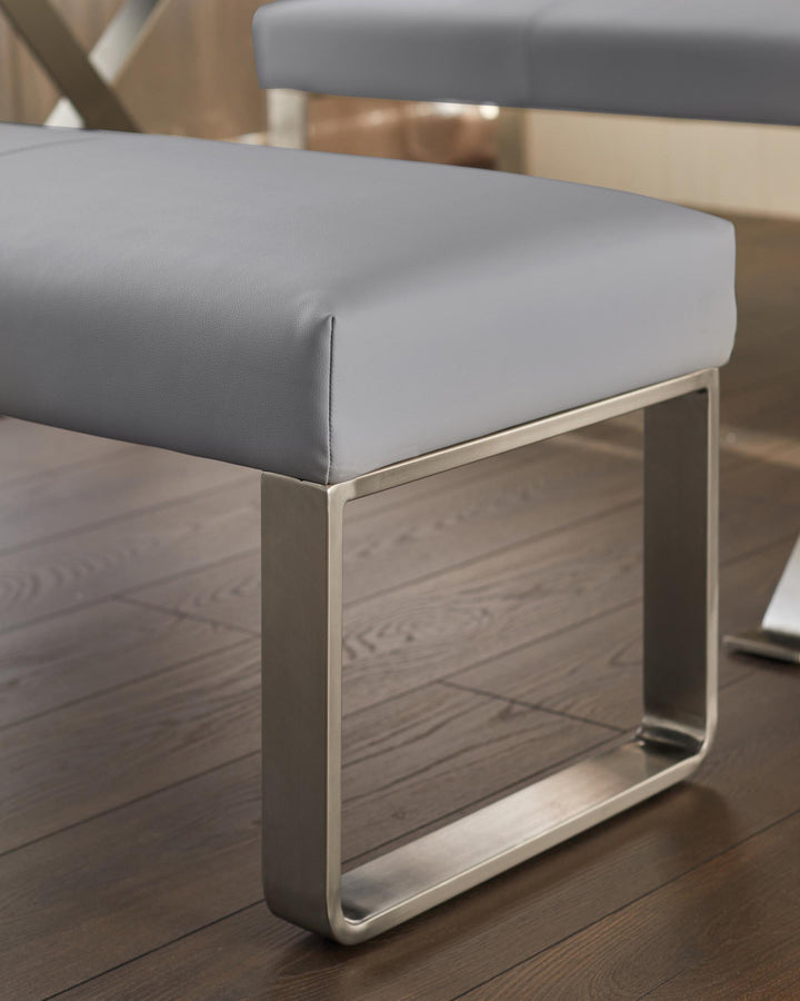 Grey padded bench seat with square tubular steel legs, displayed on a dark wooden floor.