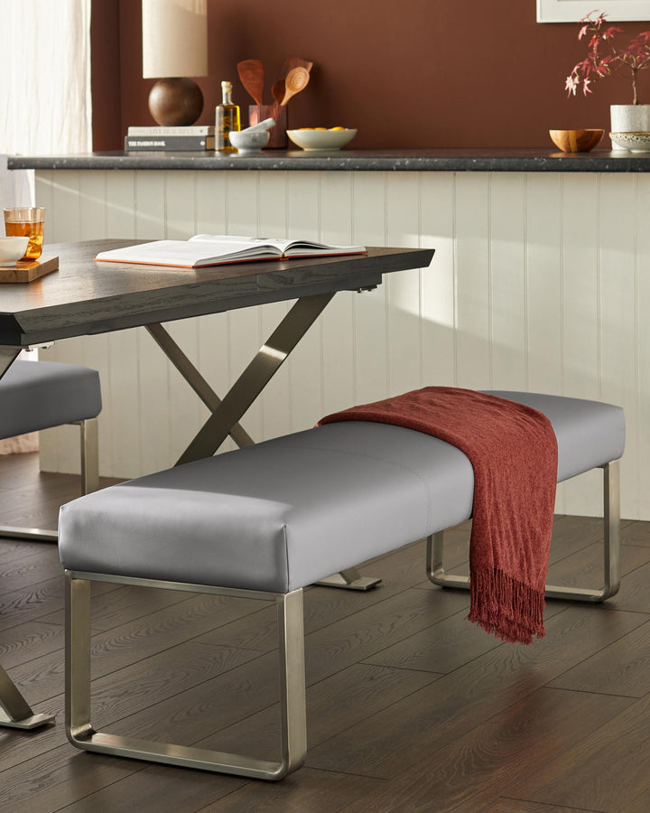 A grey bench with a throw, positioned under a dining table, showcases sleek, contemporary furniture design.