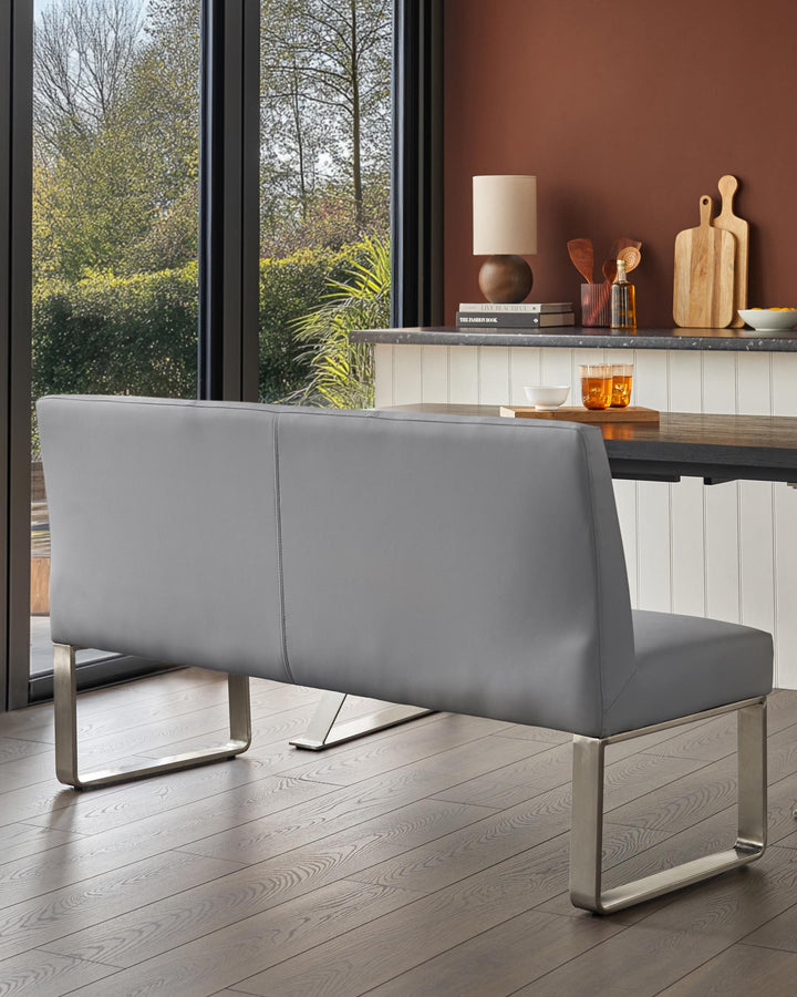 A modern grey leather dining bench with a sleek, brushed metal base. Contemporary design for the stylish home.