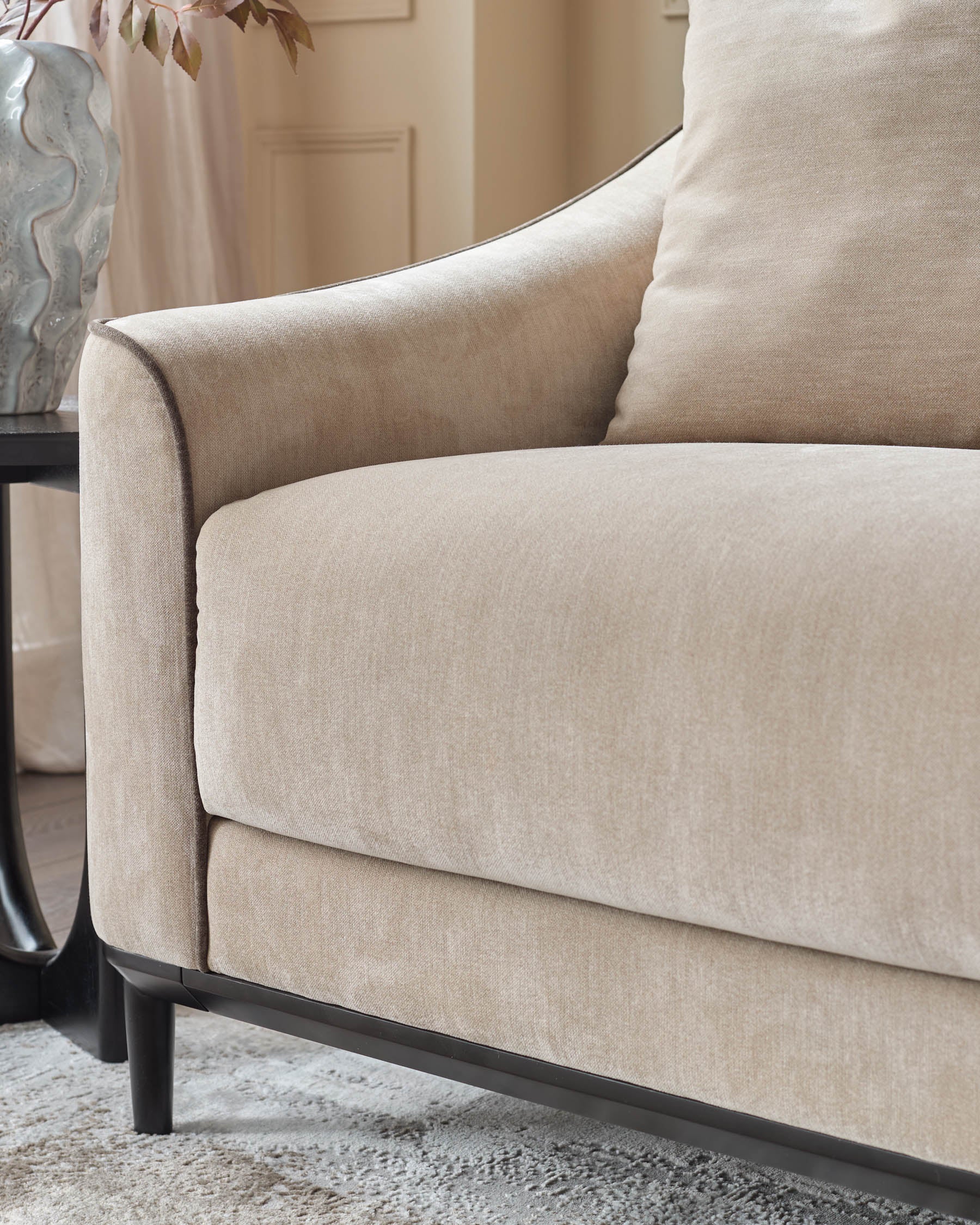 Champagne fabric 3-seater sofa with curved arms, black wooden legs, and matching throw pillow detail.