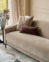 Champagne fabric 3-seater sofa with black wooden legs, styled with cream and burgundy pillows in a bright, modern room.
