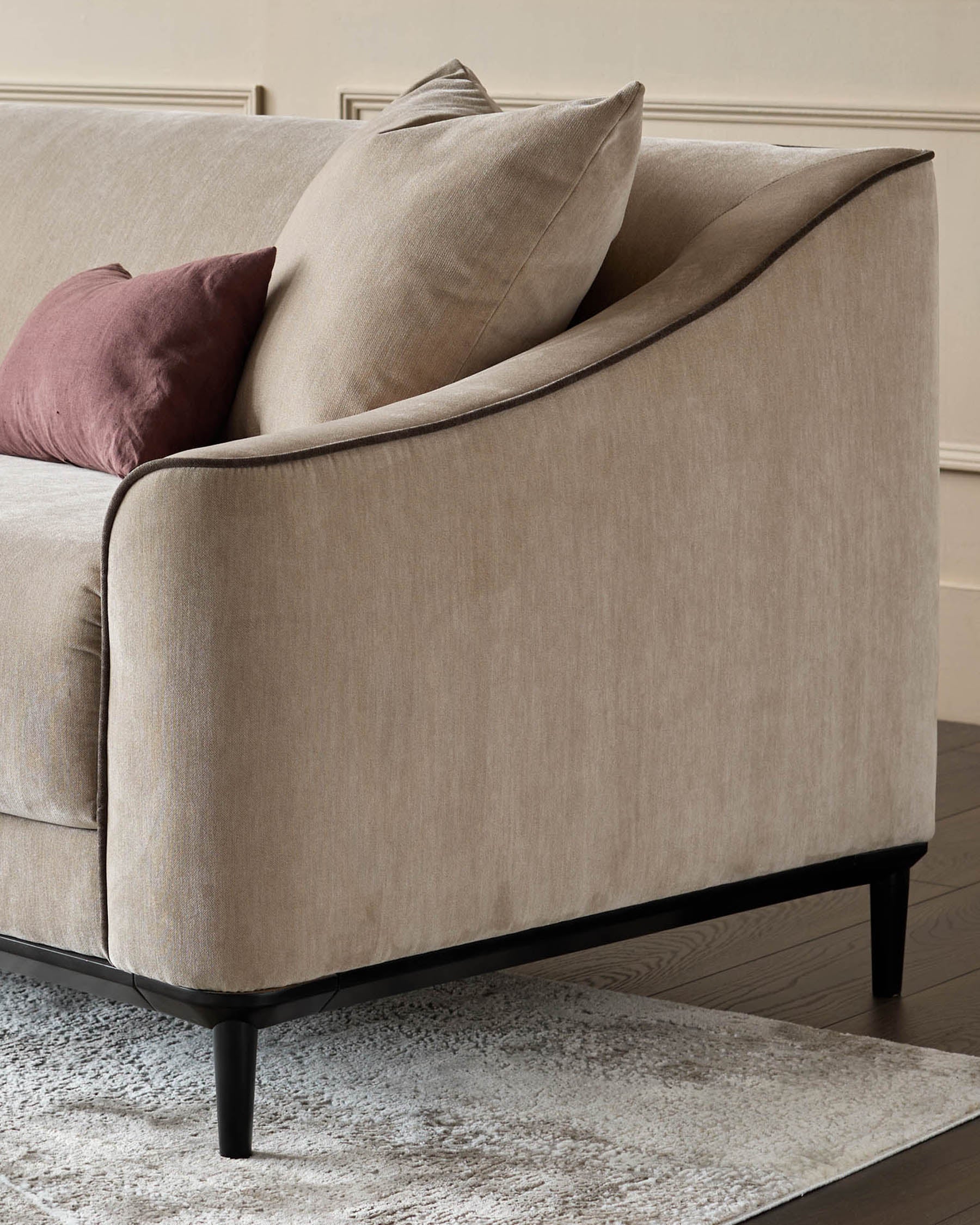 Champagne fabric 2-seater sofa with black wooden legs, shown from side angle with decorative pillows.