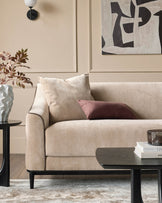 Champagne fabric 3-seater sofa with black wooden legs, styled with cream and mauve pillows in a neutral living room setting.