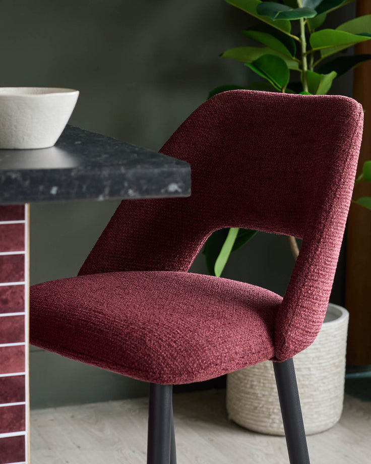 A modern red chair sits at a dark marble-effect table in this stylish shot. House plant is also visible.