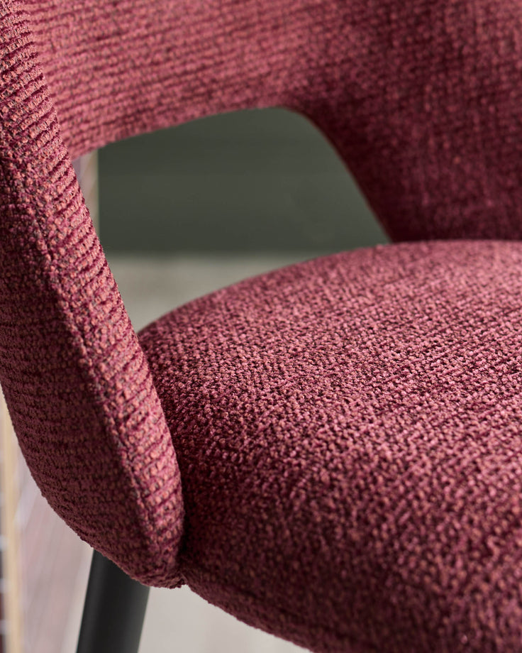 Close-up of a claret-coloured chair featuring a textured fabric on the seat and armrest, offering a tactile and inviting appearance.