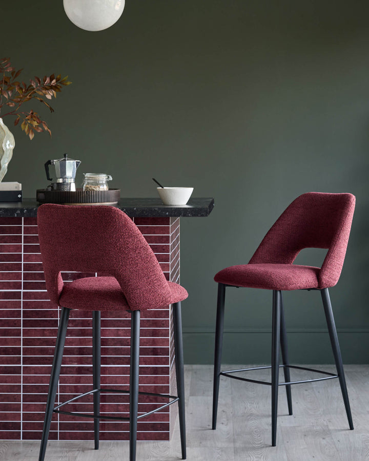 Two stylish, wine coloured bar stools with black legs next to a tiled kitchen island.