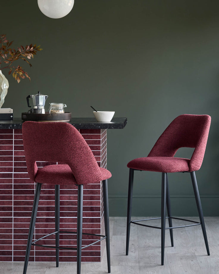 Two stylish, wine coloured bar stools with black legs next to a tiled kitchen island.