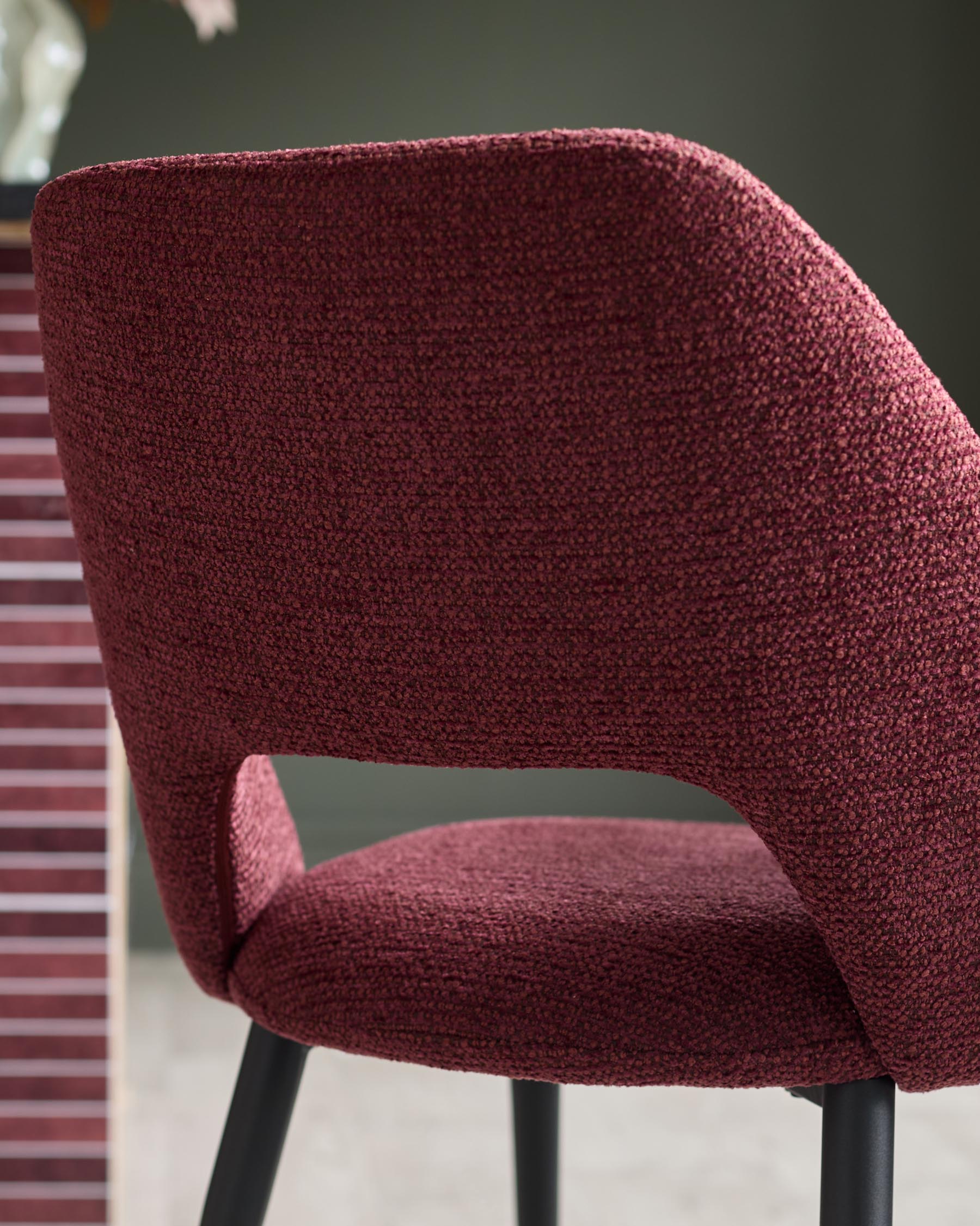 Close-up of a claret-upholstered chair with black legs, showing the backrest and seat.