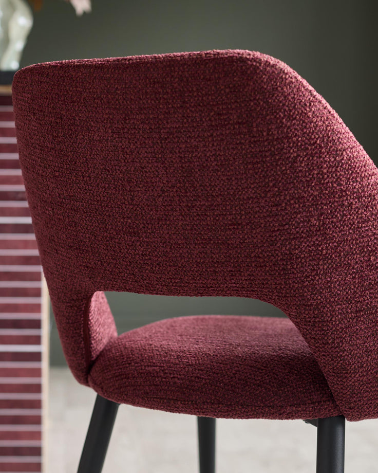 Close-up of a claret-upholstered chair with black legs, showing the backrest and seat.