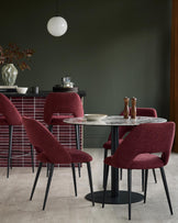 A dining area featuring a round marble table with four upholstered chairs, plus breakfast bar stools.