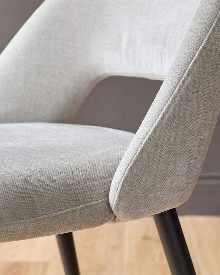 Lottie fabric dining chair in mid-grey, close-up detail showing curved armrest and seat upholstery with dark legs.