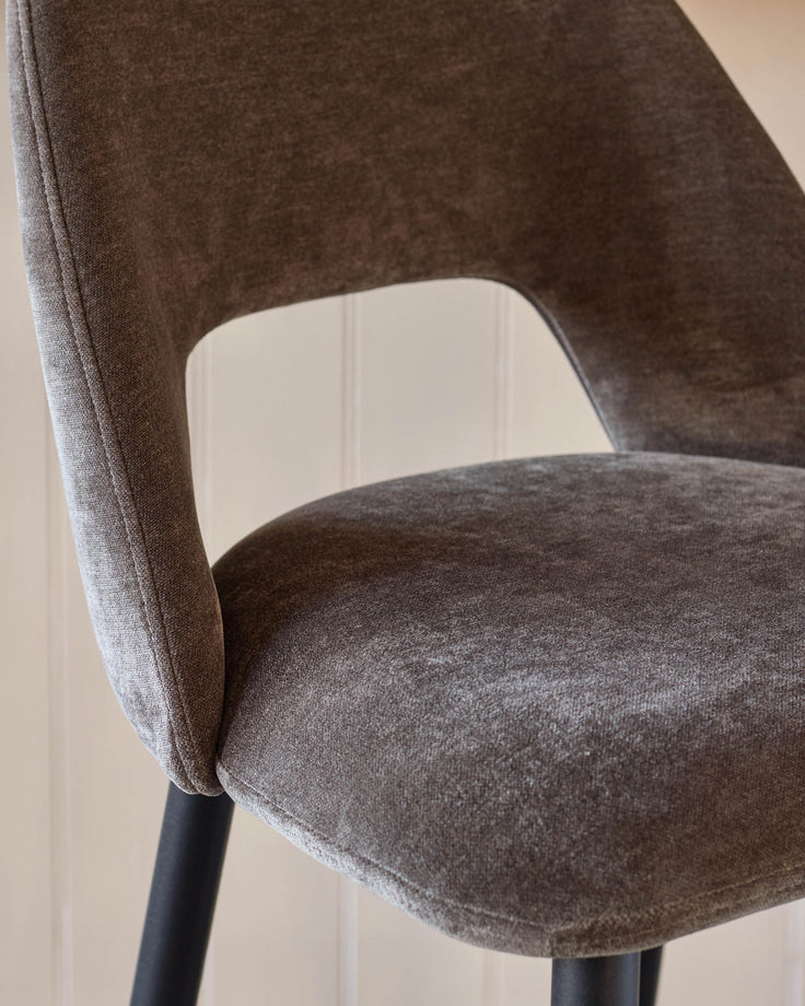 Close up of a stylish, brown, upholstered chair with black legs. Minimalist design for a contemporary home.