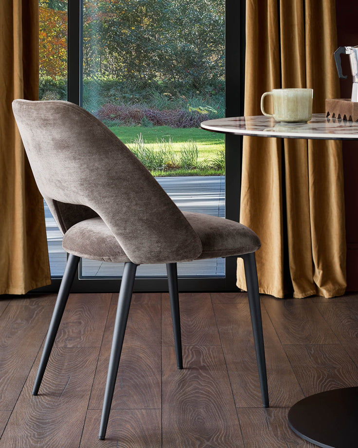 A plush, modern chair sits beside a round marble table, offering a blend of comfort and style.