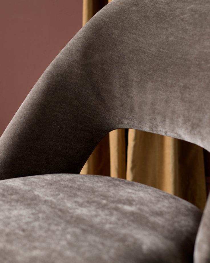 Close-up of a stylish, modern chair with curved velvet upholstery. Perfect for adding a touch of luxury to any dining space.