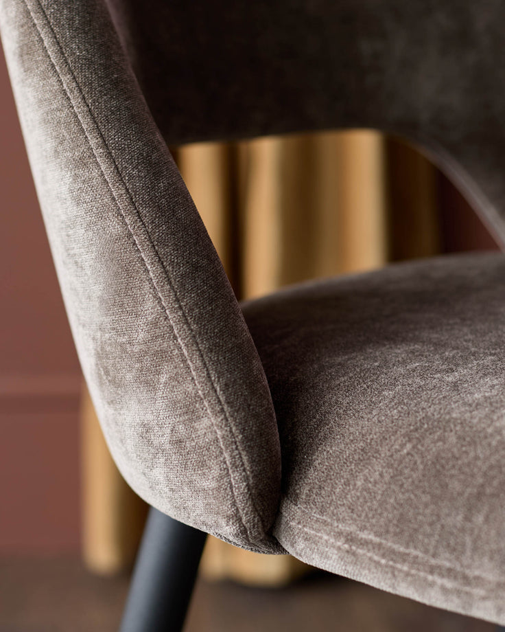 Close-up of a stylish, upholstered chair in a muted brown tone, showcasing its texture and design details.