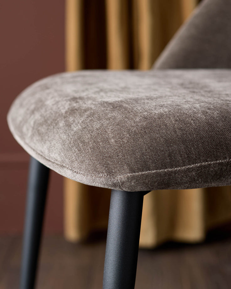 Close-up of a stylish chair featuring a brown cushioned seat and sleek black legs, exuding comfort and modern design.