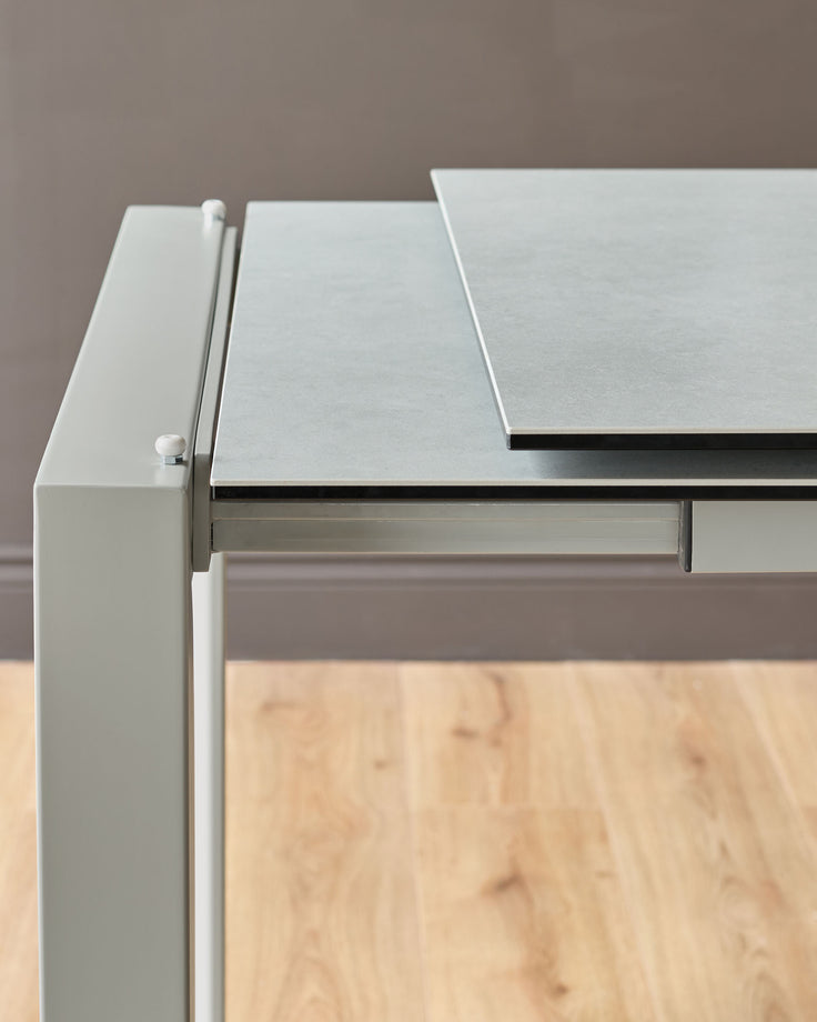 Louis ceramic extending dining table in light grey, shown from side angle highlighting the extension mechanism and white handle detail.