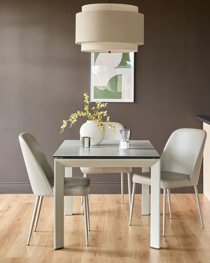 Light grey ceramic extending dining table with two cream upholstered chairs in a modern dining room setting.