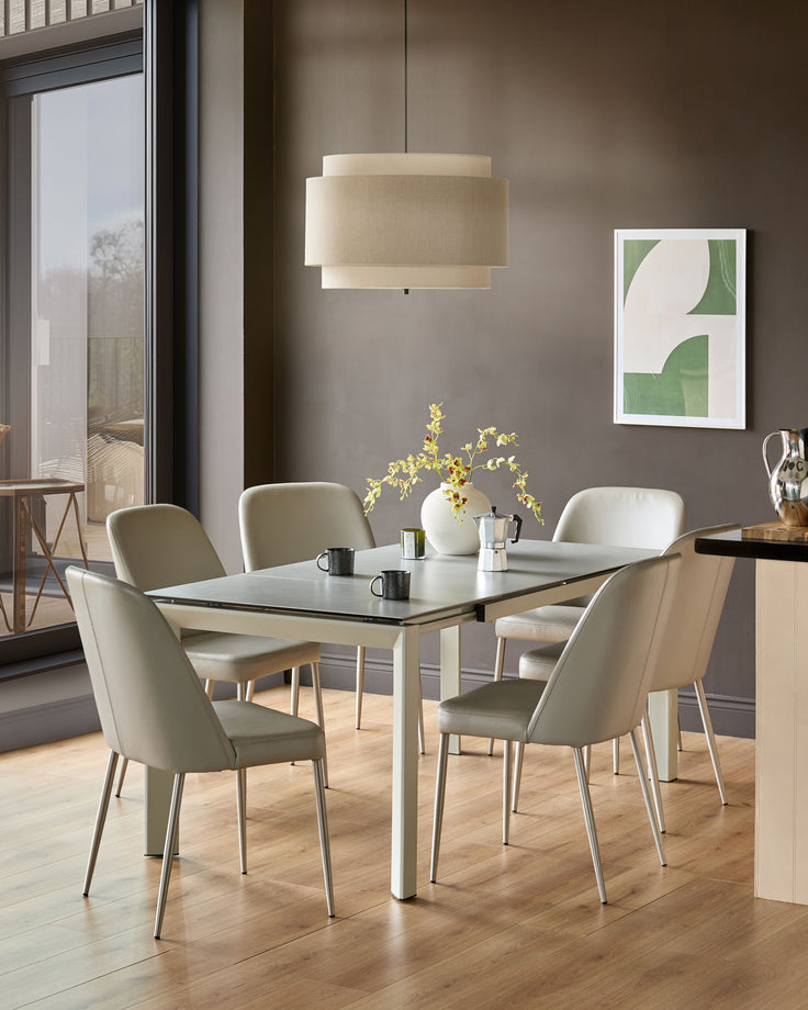 Louis ceramic extending dining table in light grey, shown extended with four matching chairs in a modern dining room setting.