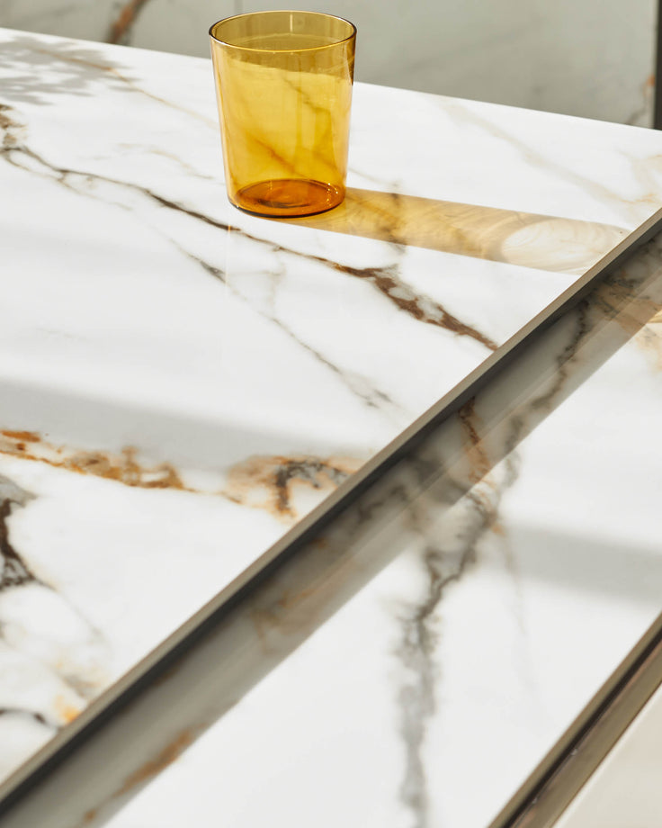 Close up of a sleek marble-effect table, with an amber glass, showcasing modern design and luxury materials.