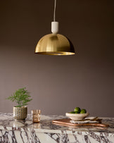 Louis single pendant brass light hanging above a marble table with interior styling.