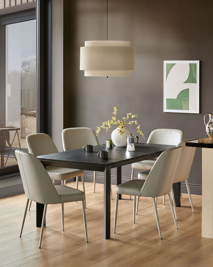 Louis ceramic extending dining table in dark grey, rectangular shape, shown in a modern dining room setting with four beige chairs.