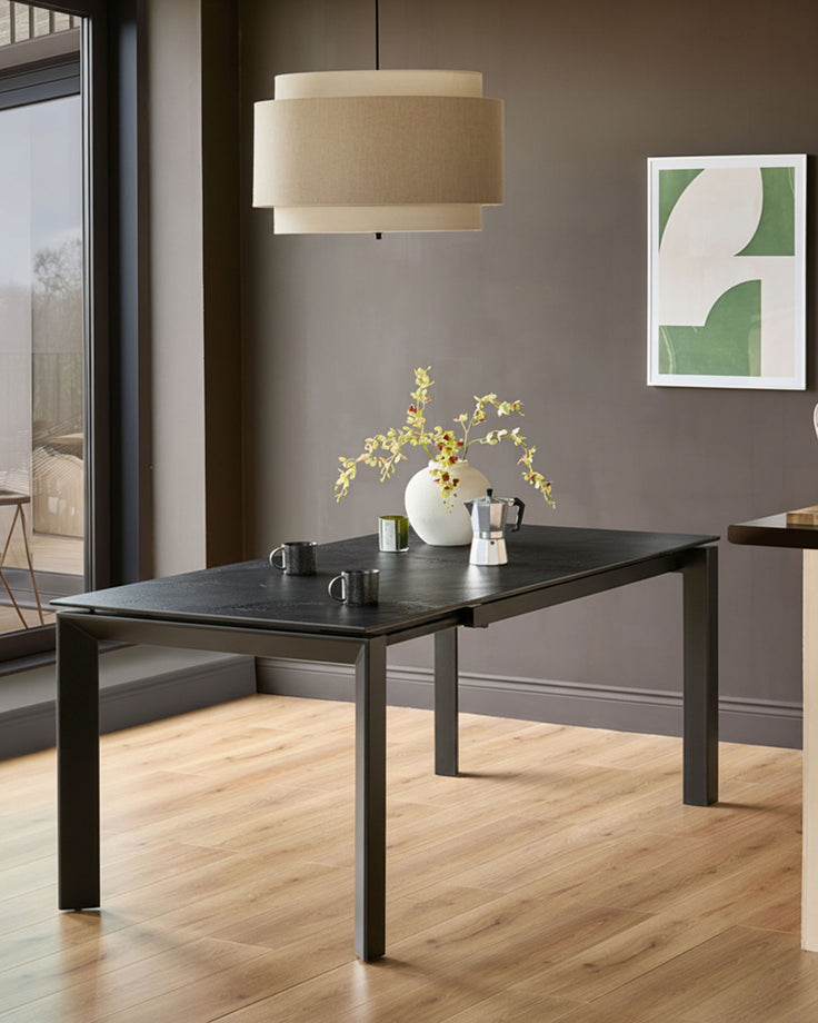 Louis ceramic extending dining table in dark grey, shown extended in a modern dining room with natural light.