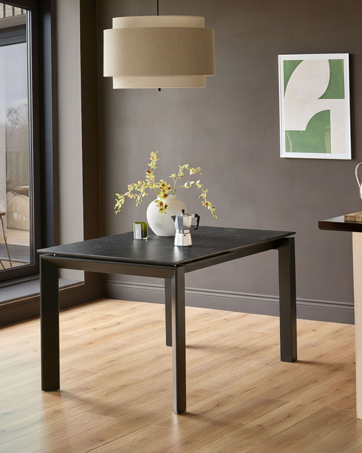 Louis ceramic extending dining table in dark grey, styled in a modern dining space with pendant lighting and tableware.