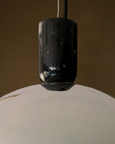 Louis single pendant with black chrome finish and white dome shade, hanging against neutral background.
