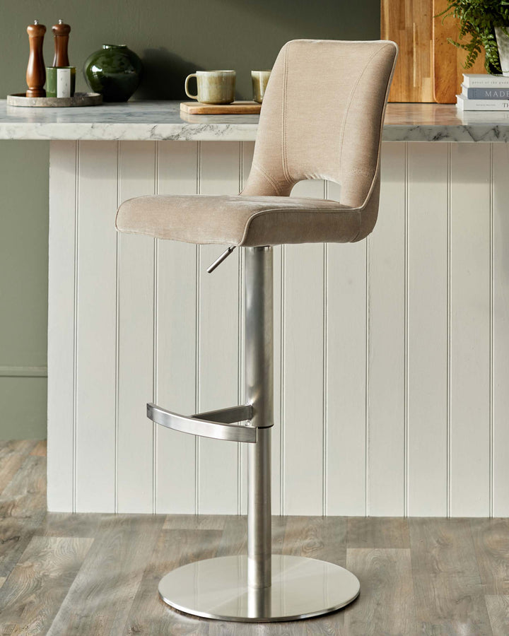 A swivelling bar stool in soft beige with a brushed metal frame and base, sitting in a stylish kitchen.