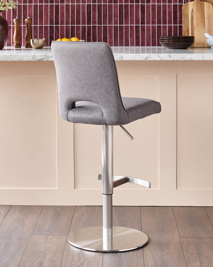 Dark grey fabric gas lift bar stool with brushed metal pedestal base and footrest, shown in kitchen setting.