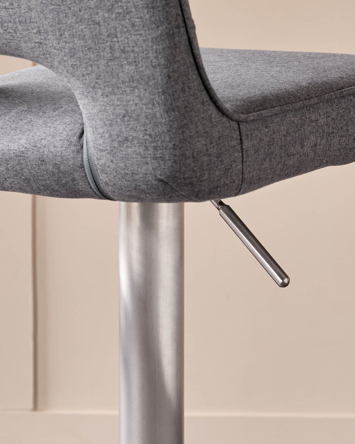 Dark grey fabric gas-lift bar stool with brushed metal pedestal base and hydraulic adjustment lever, side detail view.