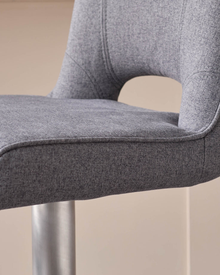 Dark grey fabric gas lift bar stool with curved backrest and chrome base, side view detail.