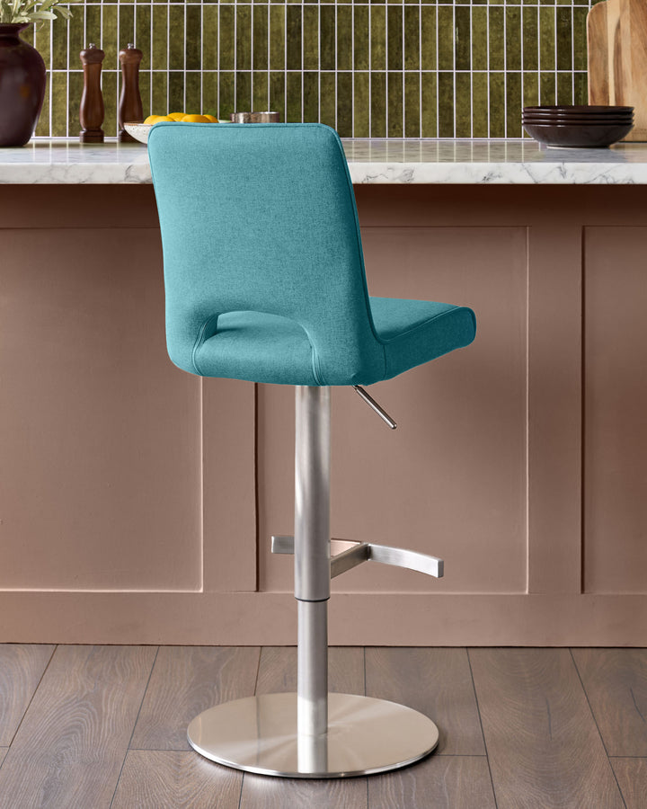 Light teal fabric gas-lift bar stool with curved back, chrome pedestal base, and footrest in modern kitchen setting.