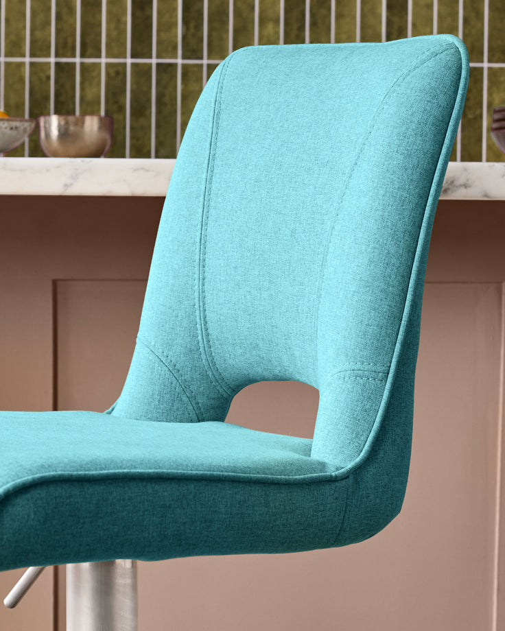 Light teal fabric gas lift bar stool with curved backrest and metal base, side view.