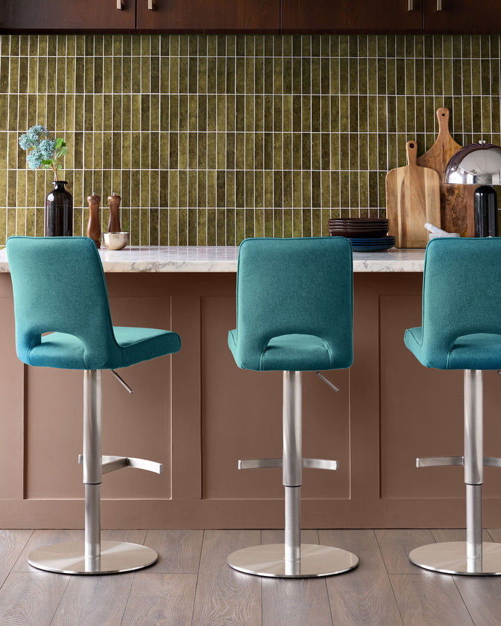 Ludo light teal fabric bar stools with chrome gas-lift bases positioned at a kitchen island counter.