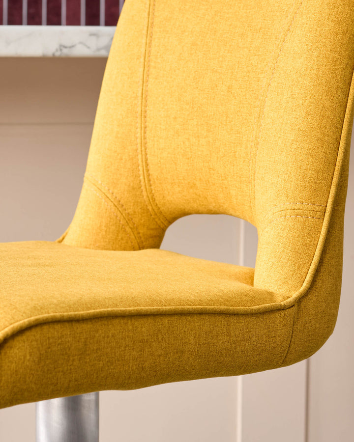 Mustard yellow fabric gas lift bar stool, side angle view showing curved backrest and seat detail.
