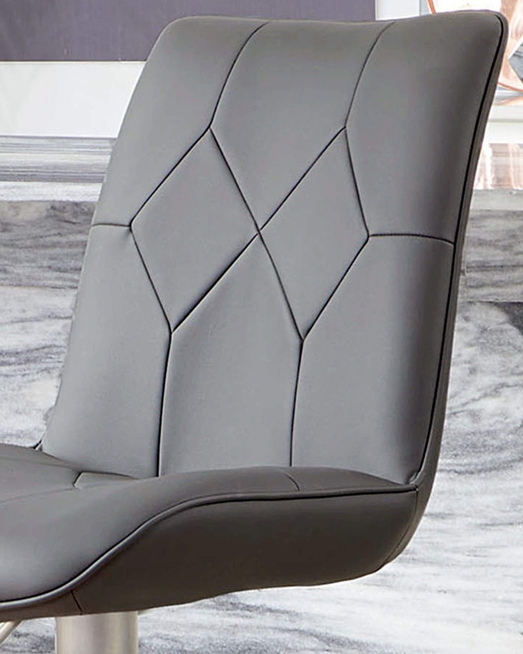 Dark grey quilted bar stool with stainless steel gas lift base, shown from side angle in showroom setting.