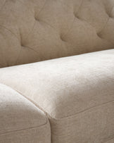 Close-up of a cream-coloured couch featuring button-tufted details and herringbone fabric.