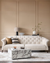 Stylish living room featuring a buttoned sofa, marble coffee table and elegant wall panelling.